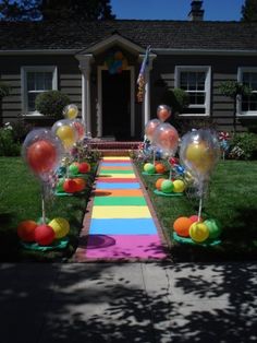 an outdoor walkway decorated with balloons and streamers in front of a house on a sunny day