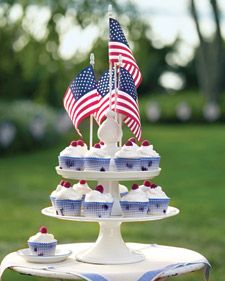 a three tiered cake stand with cupcakes and american flags on it in the grass