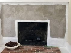 a brick fireplace is being painted with white paint and some pine cones are on the floor