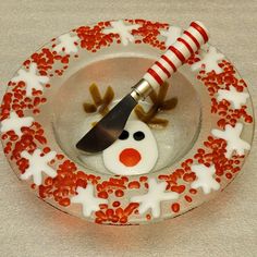 a glass plate with a snowman face on it and a knife sticking out of the top