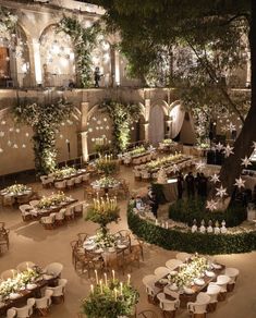 an indoor wedding venue with tables and chairs covered in greenery, surrounded by trees