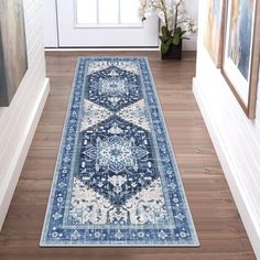 a blue and white runner rug on the floor in front of a doorway with framed pictures