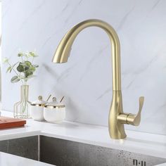 a gold faucet with water running from it's spout in a kitchen