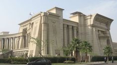 a large building with columns and pillars on the front, surrounded by palm trees in an urban area