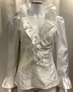 "This is an authentic 1980s ruffle blouse in white Organza. Details in include a deep V neck with large frilled collar, frilled cuffs and a fitted waist. It is fully lined and has a long zip at the back for opening. Size and fit: This top is fitted and there is no stretch to the fabric. The waist measures 28\" and the chest is approximately 36\". It would best fit a UK size 8-10. Condition: This top is in good vintage condition however, there is a pale yellowish stain around the waist area, as shown in the last photo." 80s Ruffle Blouse, Victorian Ruffle Blouse, Frill Collar Blouse, Formal V-neck Blouse With Ruffles, Elegant V-neck Ruffled Blouse, Elegant White Tops With Ruffle Hem, Elegant White Top With Ruffle Hem, Chic Fitted Ruffle Blouse, Chic Fitted Blouse With Ruffles