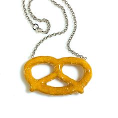 "The Jumbo Pretzel Necklace is made from a real pretzel encased in layers of our signature glitter resinthen sculpted.  Hangs on an oxidized 18\" silver plated chain" Frosted Animal Crackers, Pretzel Necklace, Donut Ring, Fish Ring, Mini Pretzels, Cheese Puffs, Animal Crackers, Food Jewelry, Pretzels