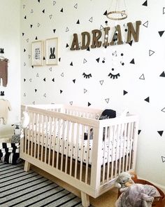 a baby's room decorated with black and white wall decals, a crib and stuffed animals