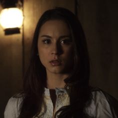 a woman with long hair standing in front of a light