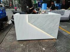 a white marble counter sitting on the side of a road next to a motorcycle parked in front of a building