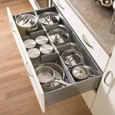 an open drawer in the middle of a kitchen with pots and pans on it