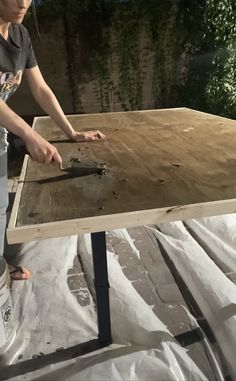 a woman is working on an unfinished table