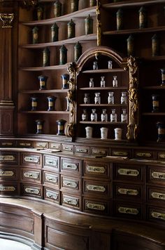 an old wooden cabinet with many vases on the top and bottom shelves in front of it