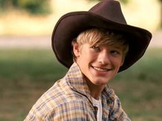 a young boy wearing a cowboy hat in the park