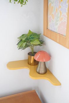 a potted plant sitting on top of a yellow shelf next to a wooden table