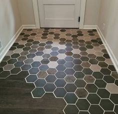 a white door is in the corner of a room with black and gray tiles on the floor