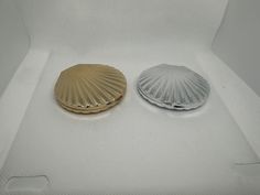 two small shells sitting on top of a white surface