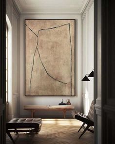 a large painting hanging on the wall above a bench in a room with wooden floors