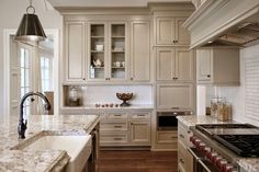 a kitchen with white cabinets and marble counter tops