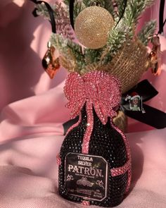 the bottle is decorated with pink and gold decorations on it's side, along with a pine tree