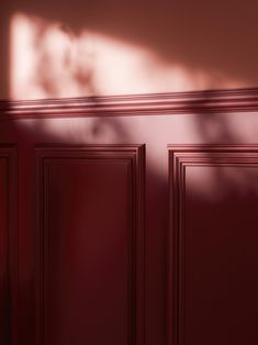 an empty room with red walls and wooden doors