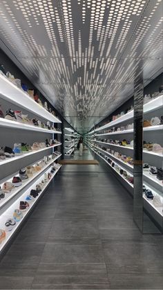 the inside of a shoe store with rows of shoes on shelves and lights hanging from the ceiling