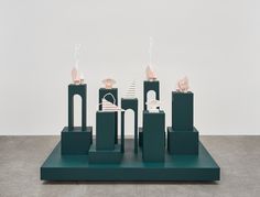 three sculptures on top of green pedestals in front of a white wall and floor