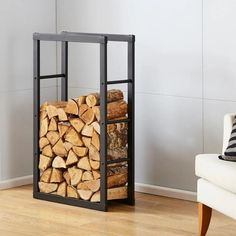 a stack of logs sitting in front of a white chair on top of a hard wood floor