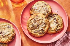 chocolate chip cookies on pink plates next to an orange napkin