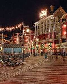 the boardwalk at night is lit up with christmas lights and decorations on it's sides