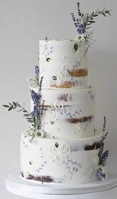 a three tiered cake with flowers and leaves on the top is sitting on a white plate