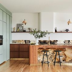 a kitchen with wooden cabinets and marble counter tops, along with a bar stool in the center