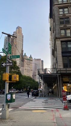 an intersection in the middle of a city with tall buildings on both sides and people walking down the street