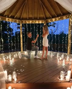 a man kneeling down next to a woman on top of a wooden floor covered in candles