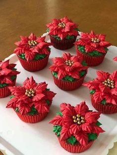 cupcakes decorated with red poinsettias on a white tray