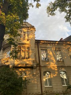 an old building with lots of windows and trees in front of it on a sunny day