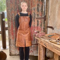 a woman wearing an apron standing next to a wooden table