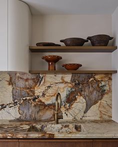 a kitchen with marble counter tops and bowls on shelves above the sink in front of it