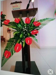 a podium with red flowers and greenery on it