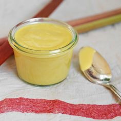 a glass jar filled with yellow liquid next to two spoons