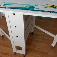 a white table with some drawers on it and a pair of scissor's