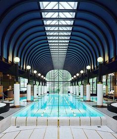 an indoor swimming pool in a large building with skylights and benches on the side