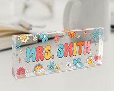 the name mrs smith is painted on an acrylic block with flowers and rainbows