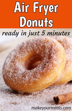 two sugared doughnuts sitting on top of a table next to cinnamon sticks