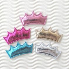 three different colored crowns sitting next to each other on top of a white tablecloth