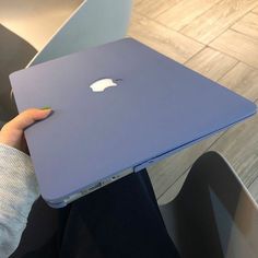 a person holding an apple laptop in their hand