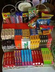 an assortment of candy bars and snacks on a metal rack in front of a table