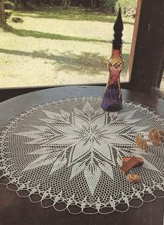 a crocheted doily is sitting on a table in front of a window