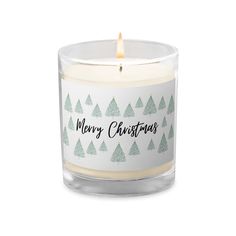 a glass candle that says merry christmas with trees on the front and bottom in black lettering