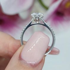 a close up of a person's hand holding a ring with a diamond on it