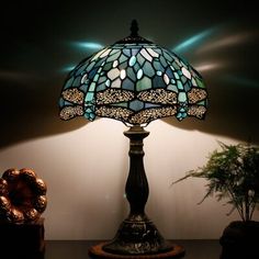 a lamp sitting on top of a wooden table next to a potted green plant